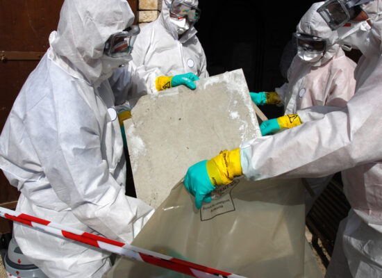"Staff removing some asbestos in a post of transformer, Reflection of mask of man opposite was created for cannot be recognized"